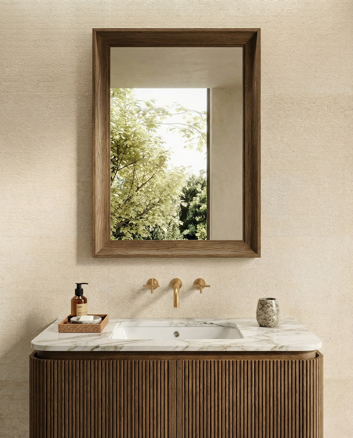 Bathroom vanity with wooden cabinet, marble countertop, and framed mirror reflecting greenery.
