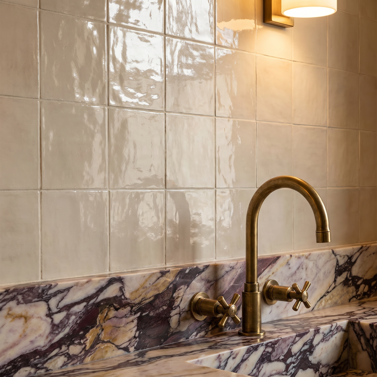 Brass faucet on a marble countertop with tiled wall in the background