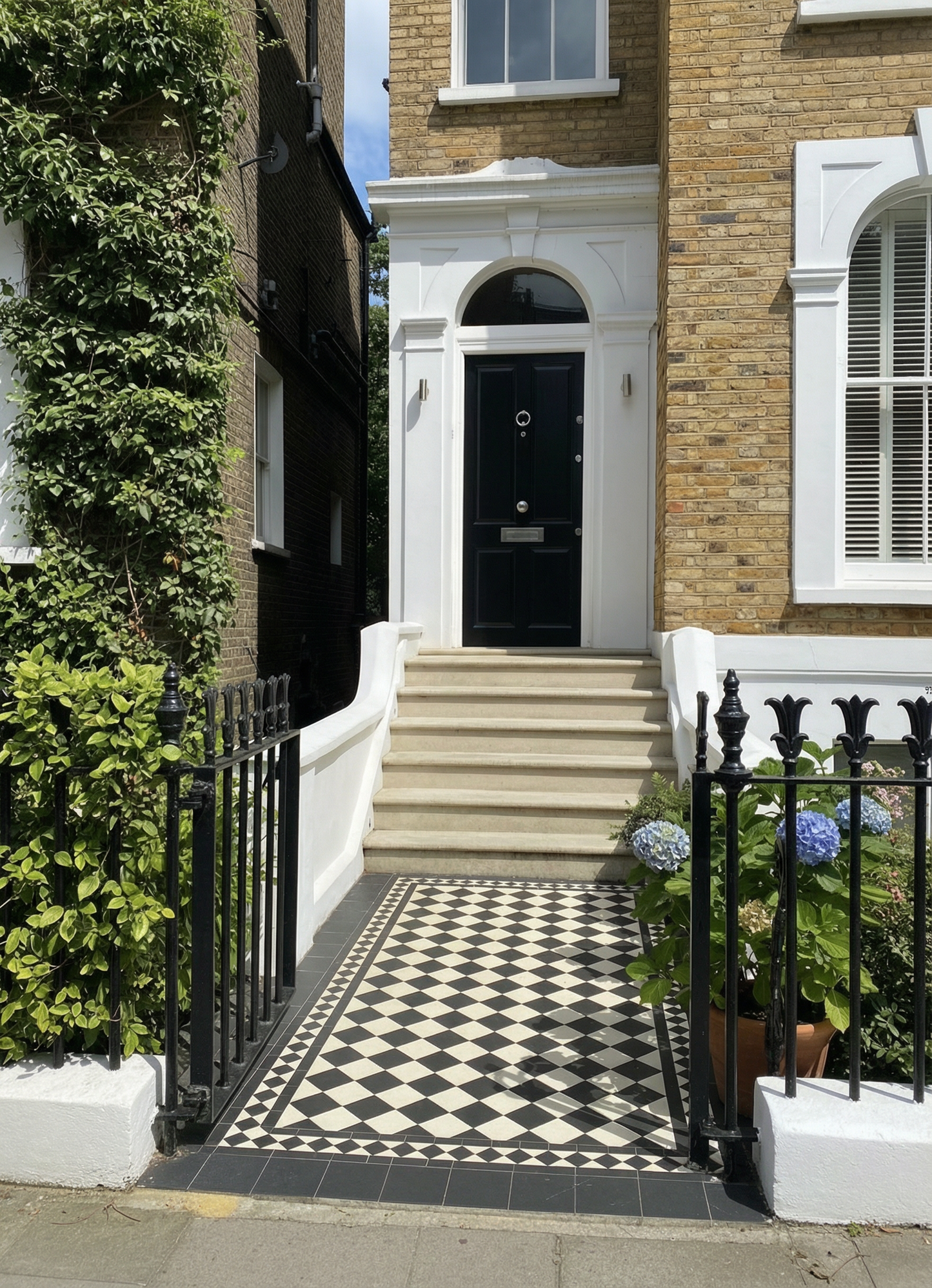 London home entrance with black door, steps, and decorative black and white tiles.