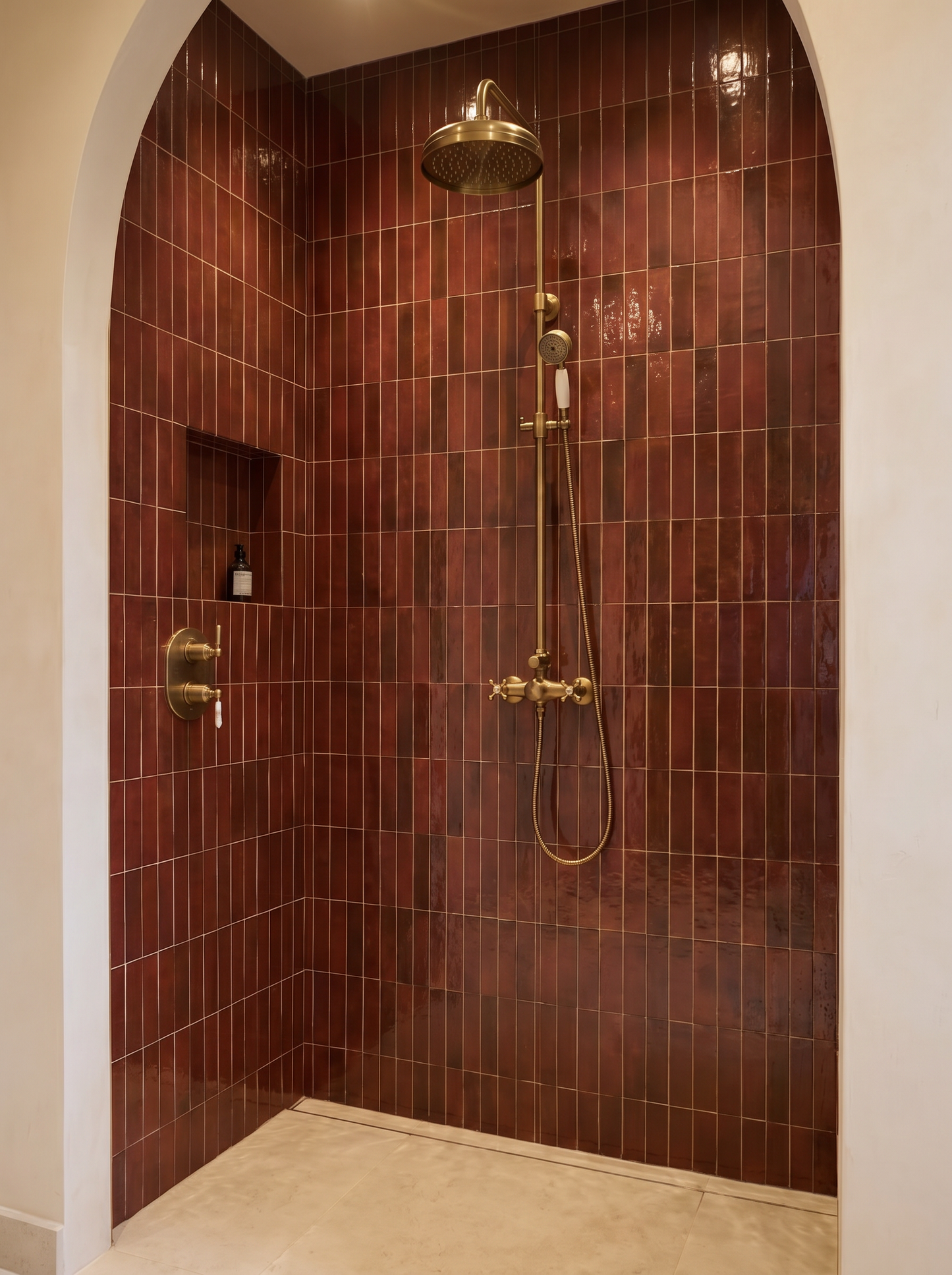 Shower with red tiled walls and gold fixtures