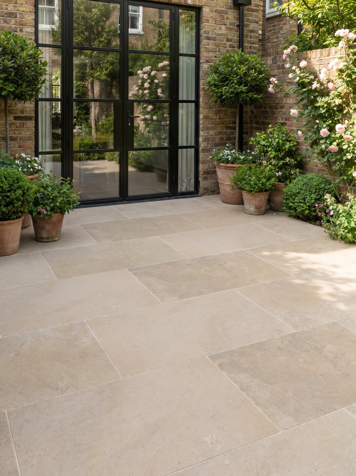Paved patio area with potted plants and a glass door in the background