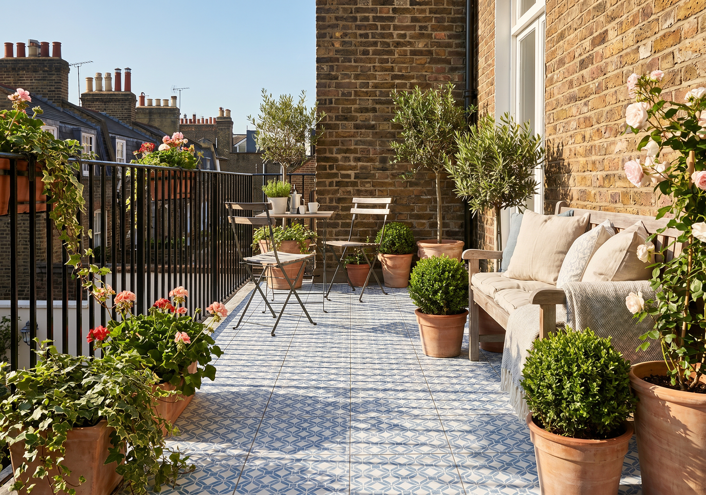 Tiled outdoor patio with furniture, plants, and a view of neighboring houses.